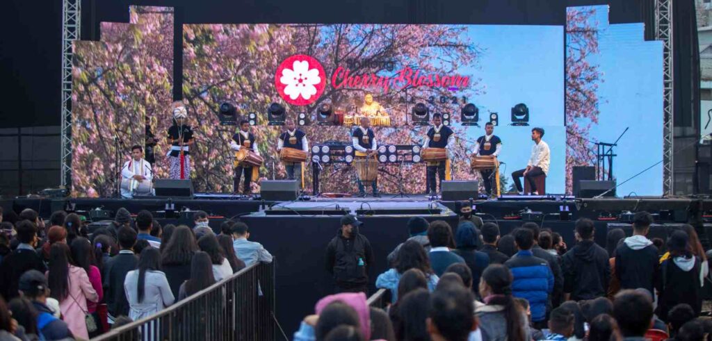 Traditional performance on stage during the Cherry Blossom Festival in Shillong, with a lively audience.